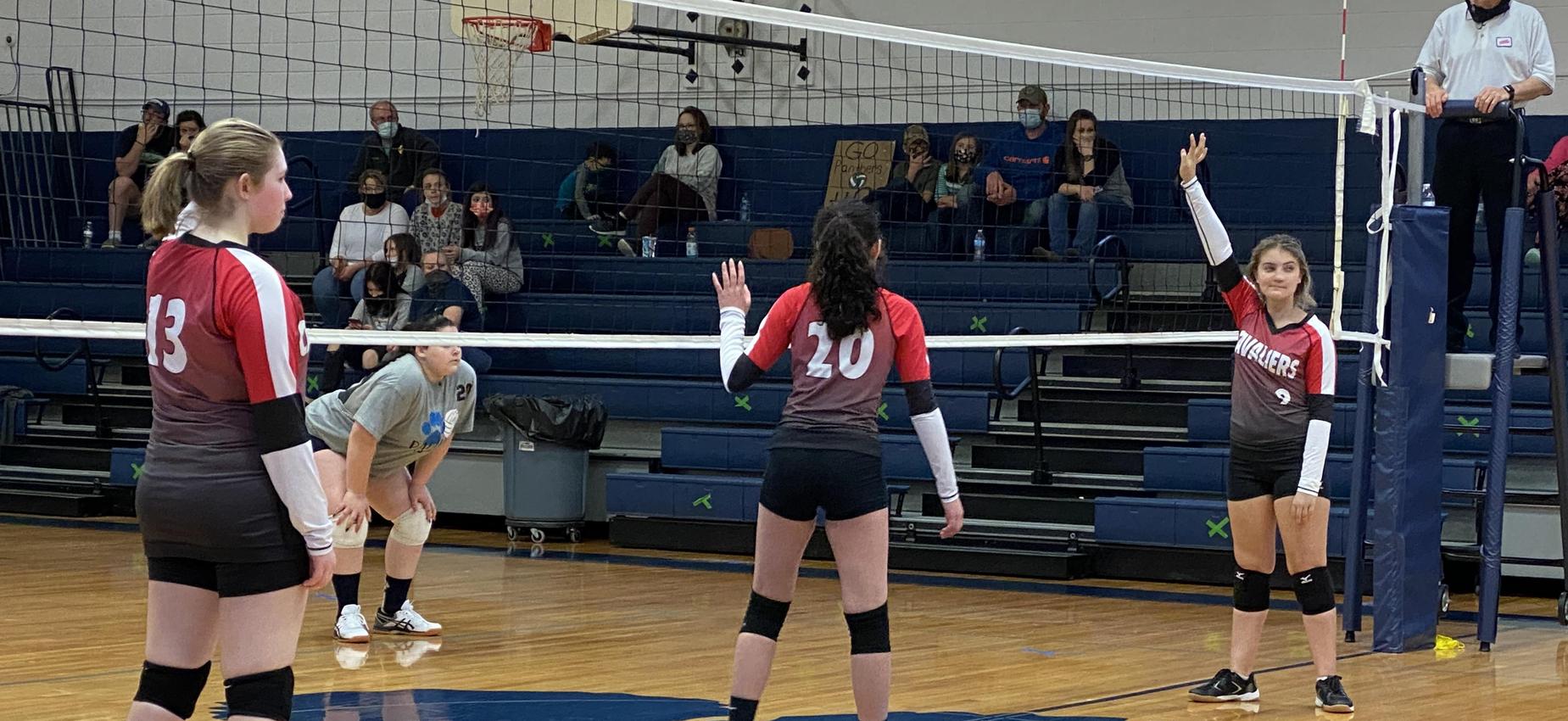 Volleyball players play in a gym.