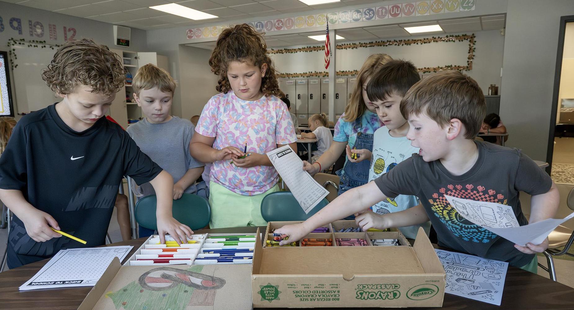 Students grab markers from boxes.