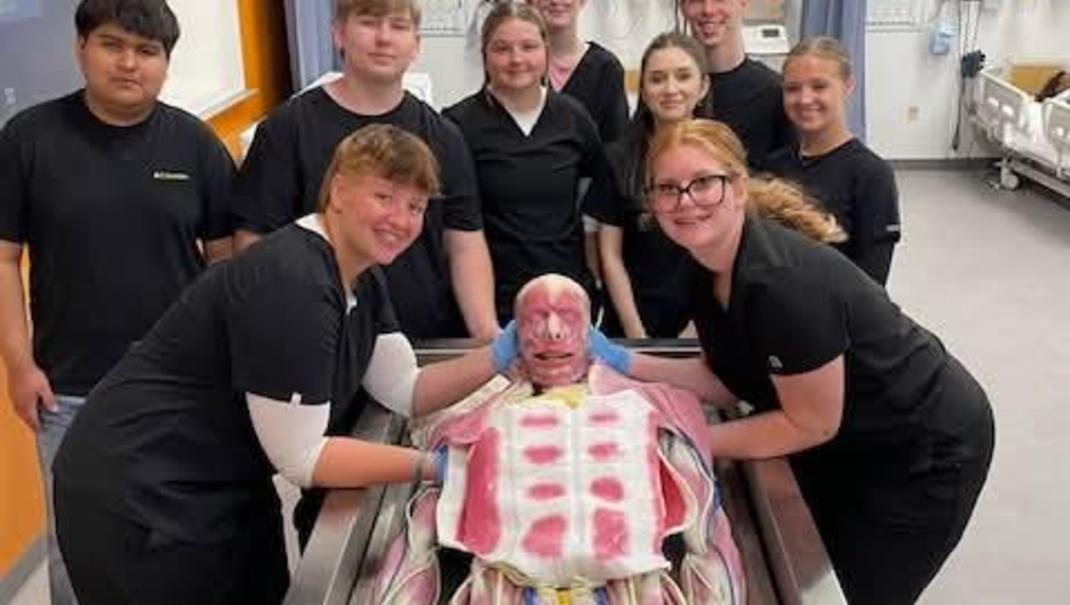 Students posing with a large model in a classroom.