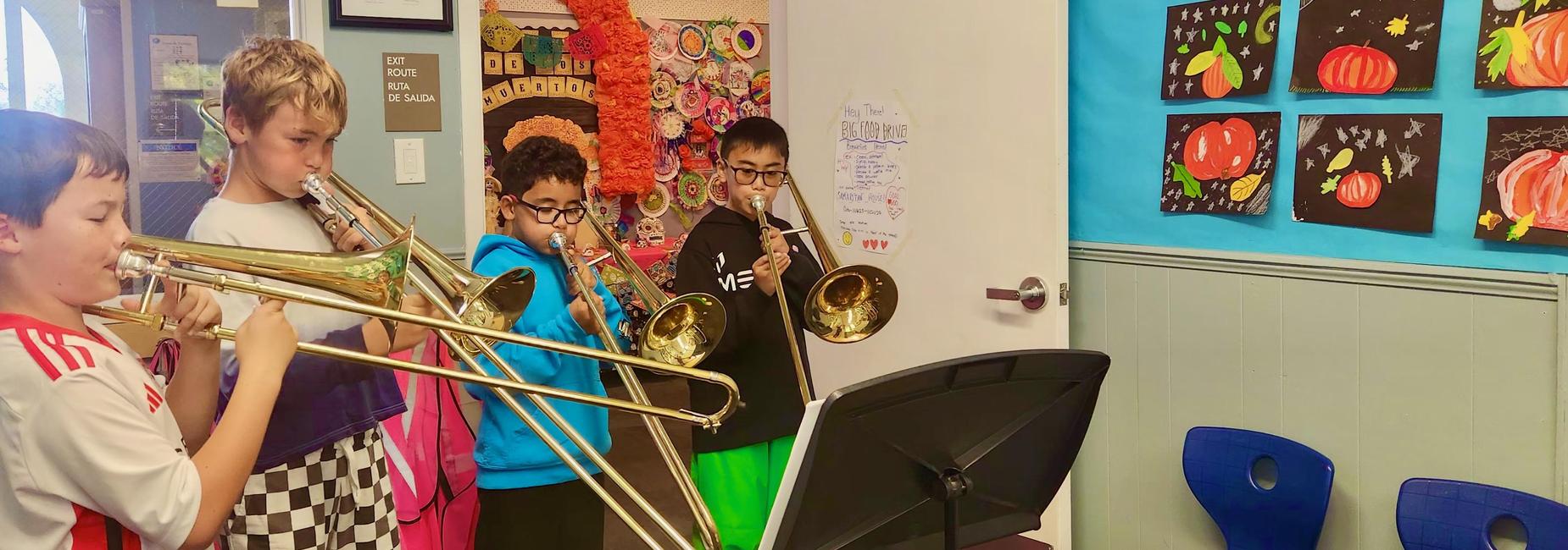 Four McKinley students are playing trombones in a colorful office.