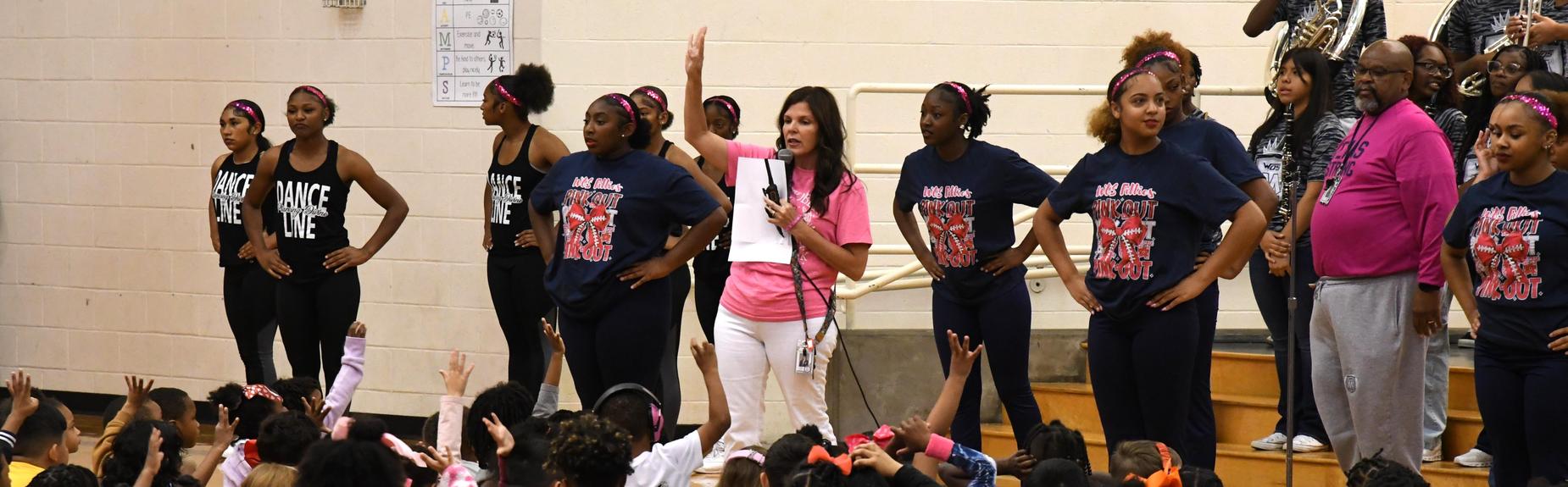 A group of performers engaging with an excited audience of children in a gymnasium.
