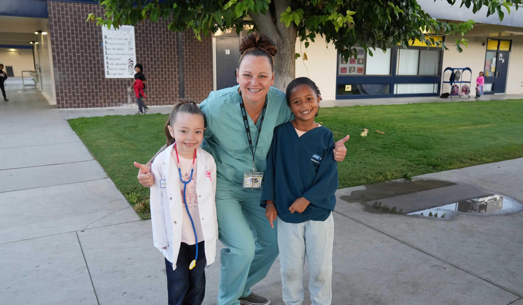 two students and aide dressed up like doctors