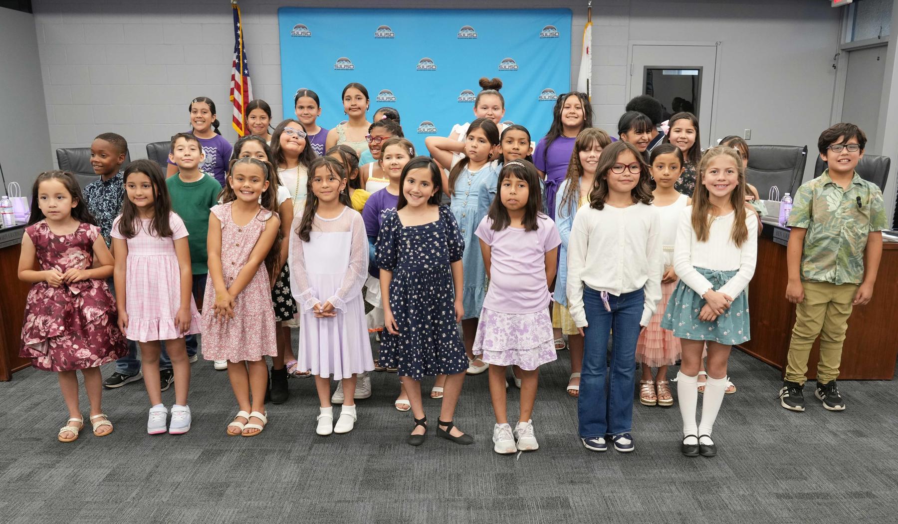 Group of children in colorful outfits posing together in a formal setting.