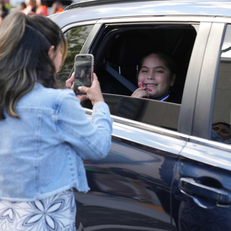 Staff member taking photo of smiling student in a car