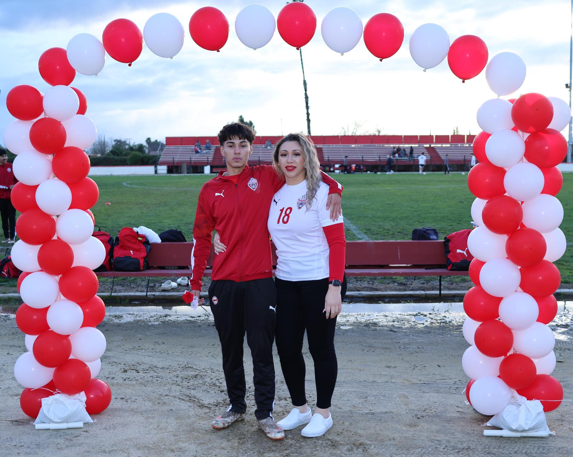seniors and their escorts posing beneath a balloon arch