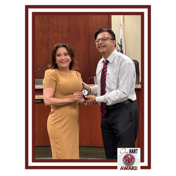 A man and woman exchanging an award in a formal setting.