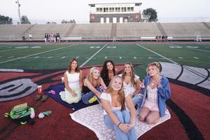 A group of seniors pose for a photo on the field.