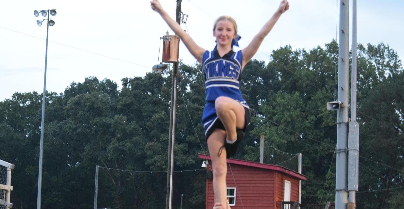 A cheerleader is being lifted by teammates during a performance.