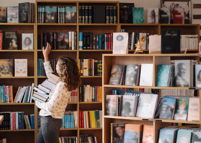 Person browsing bookshelves in a cozy library setting.