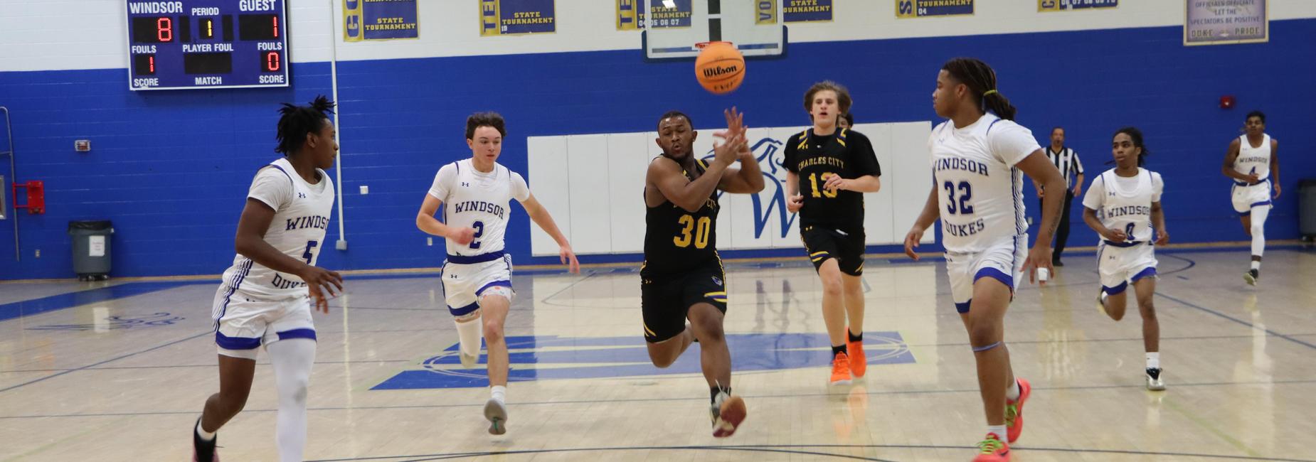 Basketball players competing for the ball on a gym court.