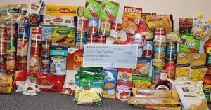 a large check in front of canned goods and non perishables