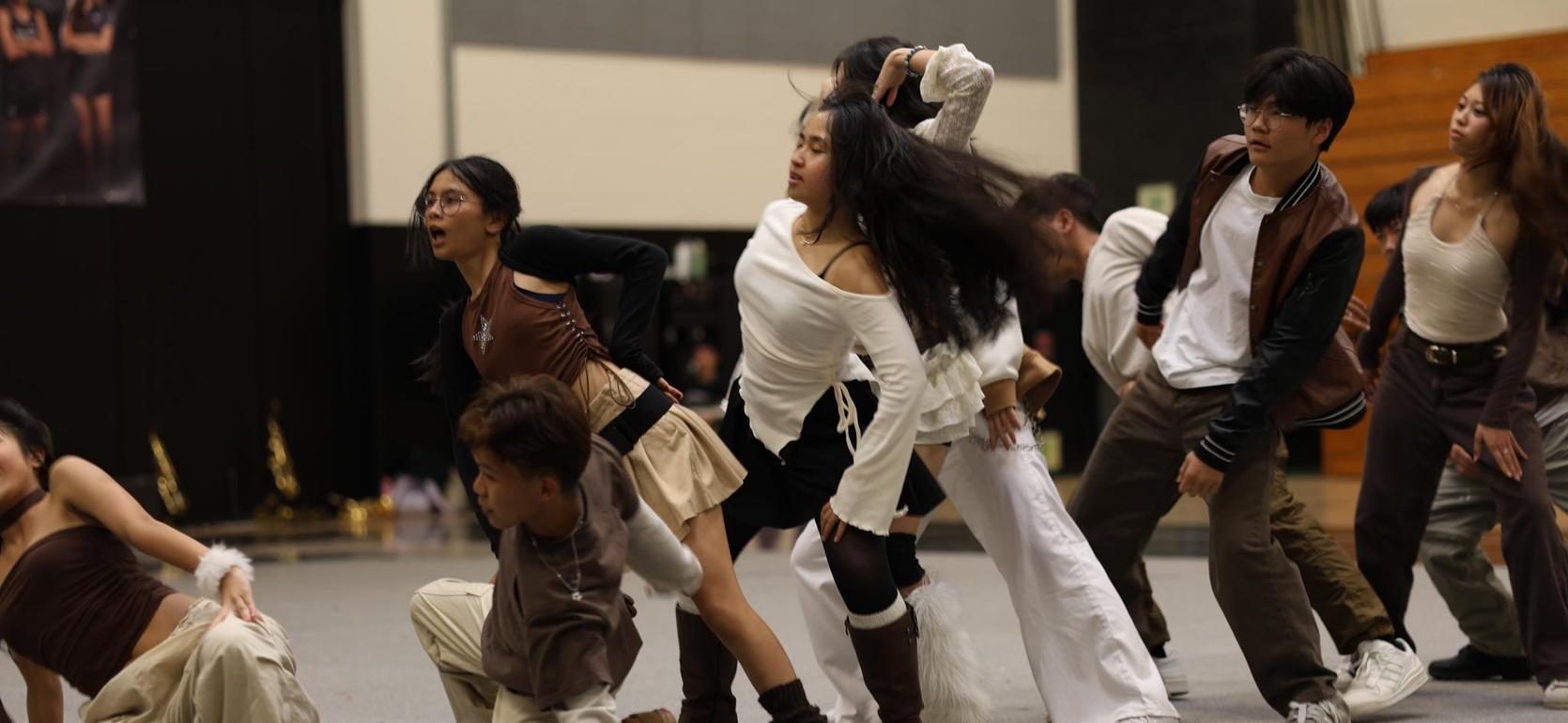 A dynamic dance group performing on stage with expressive movements and diverse outfits.