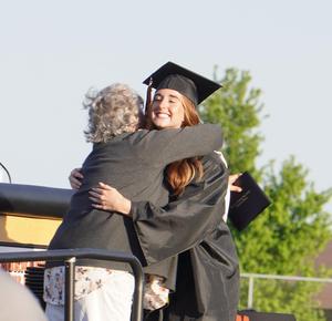 A graduate gets a hug after receiving her diploma.