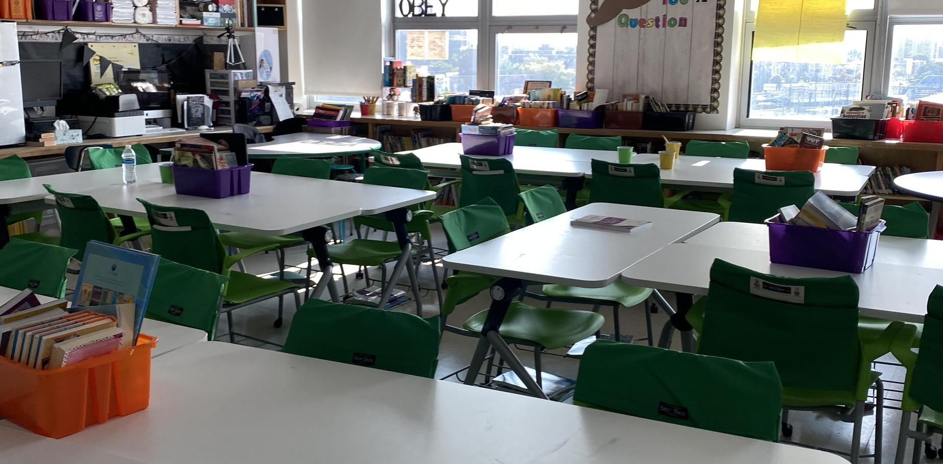 Empty classroom with tables and organized book bins.