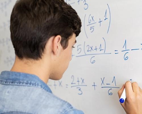 Student works on a math problem on a whitebraod