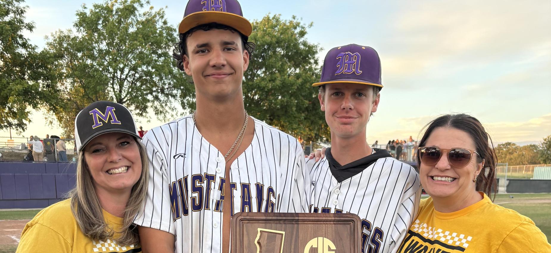 Three people celebrating with a championship plaque in a baseball field.
