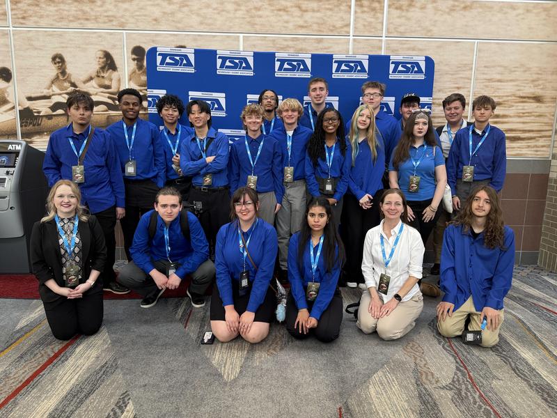 Students in blue shirts posing for team photo
