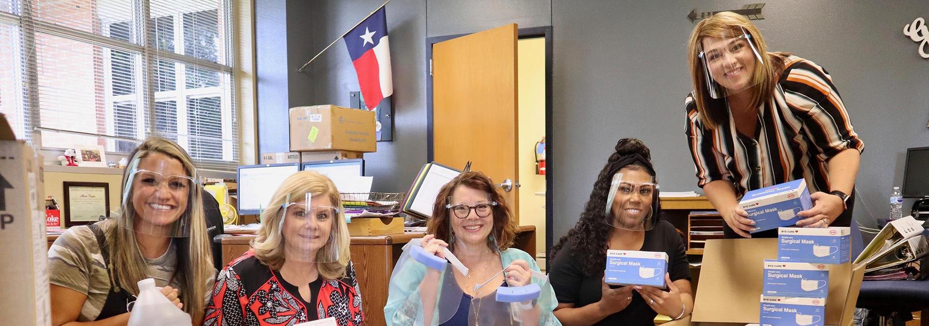ladies in face coverings unpacking boxed of ppe