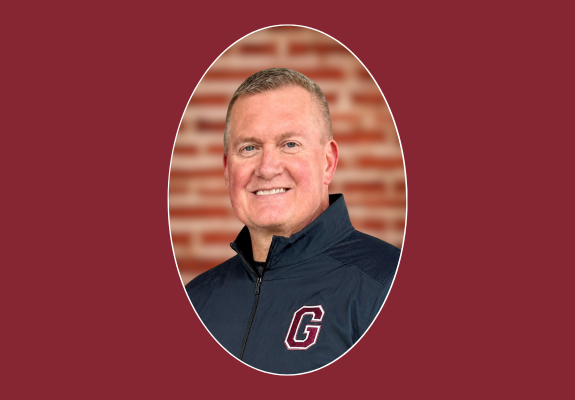 portrait of Mr. Bearup in a black jacket with block G maroon logo in front of brick backdrop