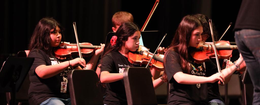 Children playing violins during an orchestra performance.