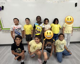 Group of children wearing yellow shirts with playful emoji faces.
