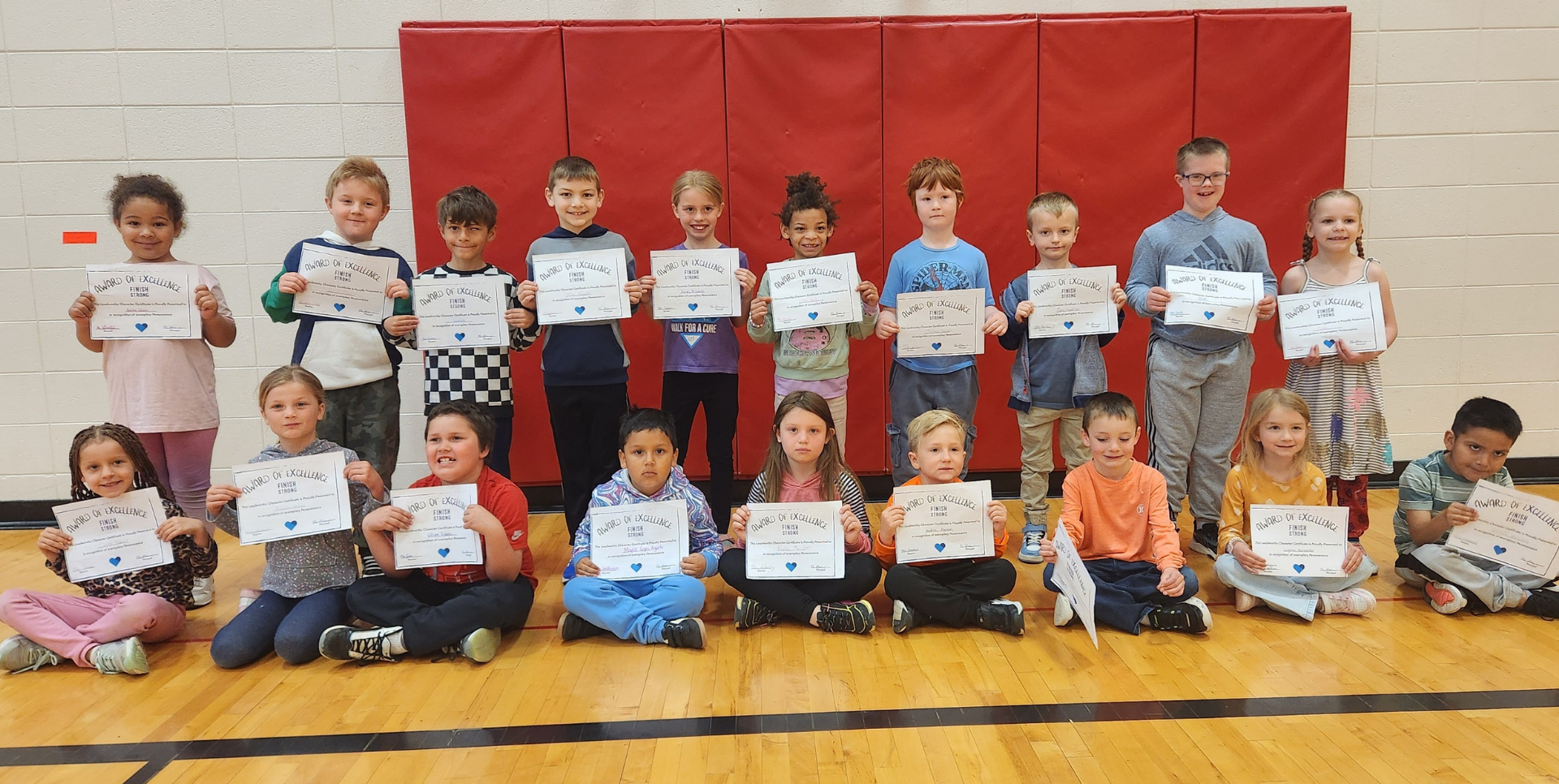 Group of students holding certificates in a gym setting.