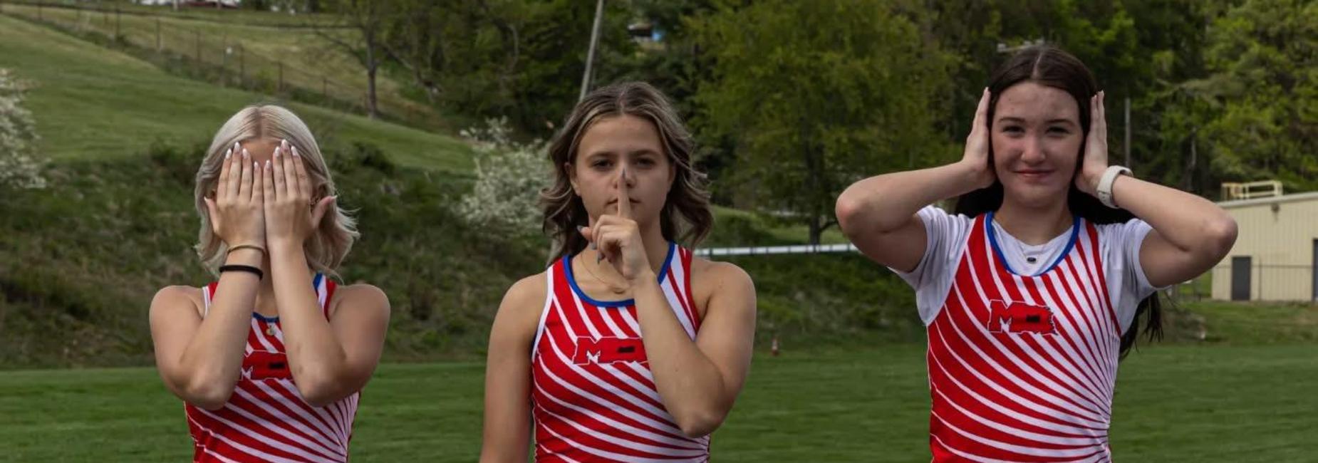 three track athletes posing with one covering face, one with her finger over her mouth and one covering her ears.