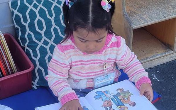 Girl reading a book outdoors.