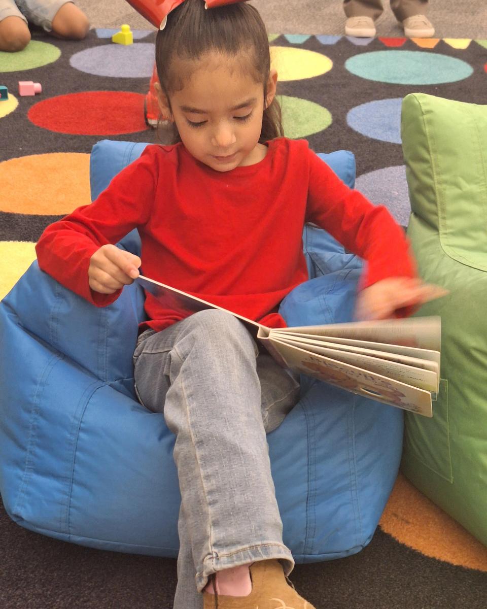 A PK student enjoying a book and comfy seating.