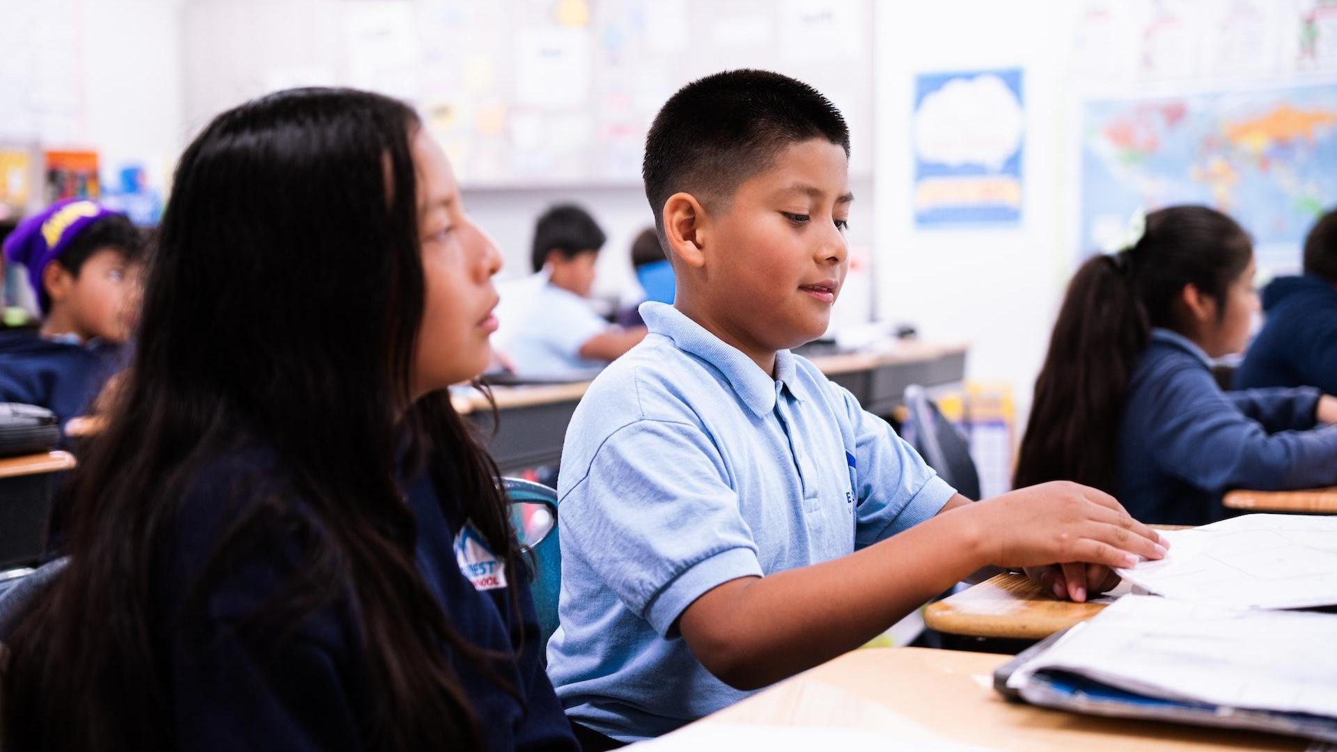 Two students discussing schoolwork in a vibrant classroom setting.