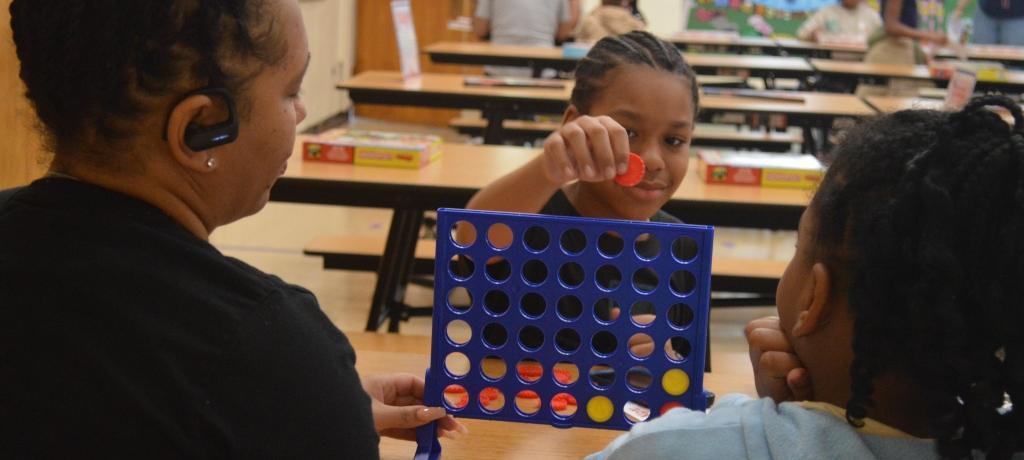 boy places red chip into a Connect Four frame