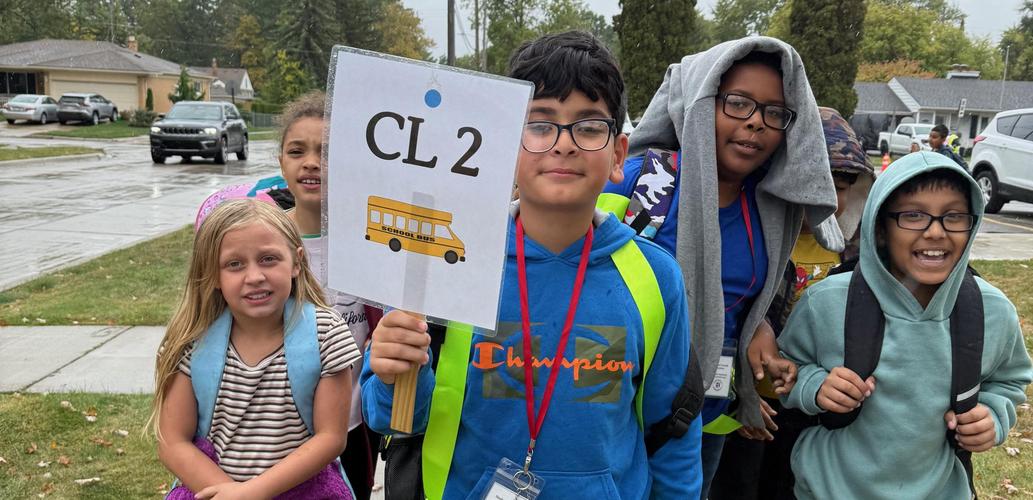 students standing outside in line with student bus line leader