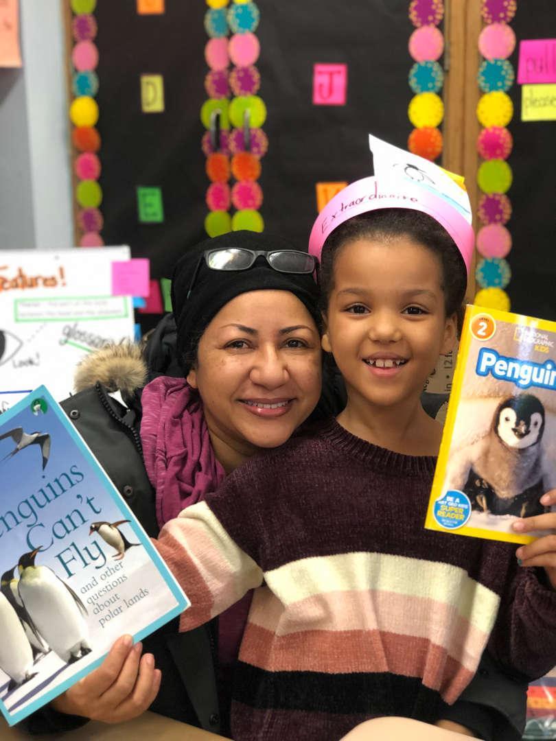 Woman and child posing with children's books in a classroom setting.