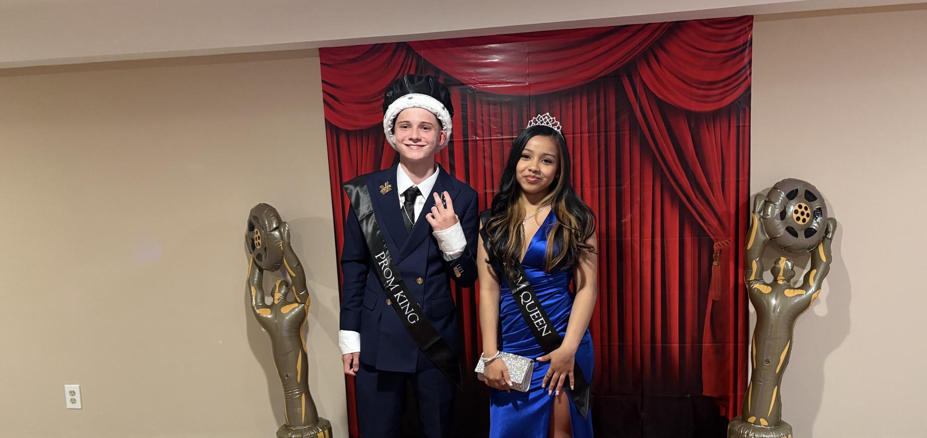 Two students voted prom king and prom queen standing in from of movie style background