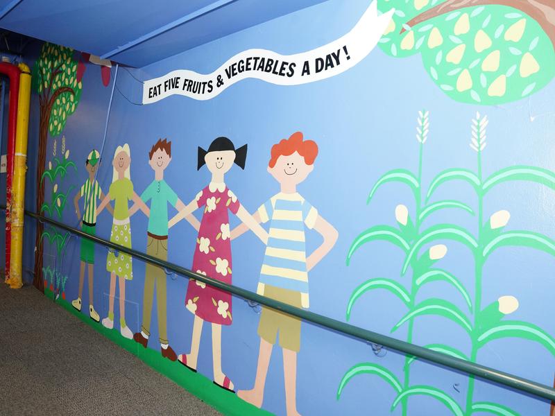 A mural outside the WIC Clinic showing people standing linked together