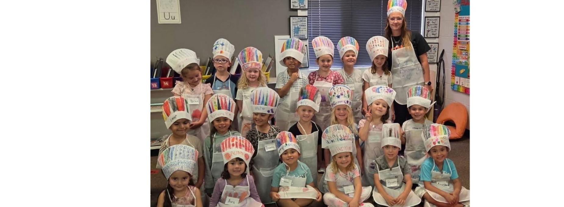 BES children wearing chef hats and aprons smiling for the camera.