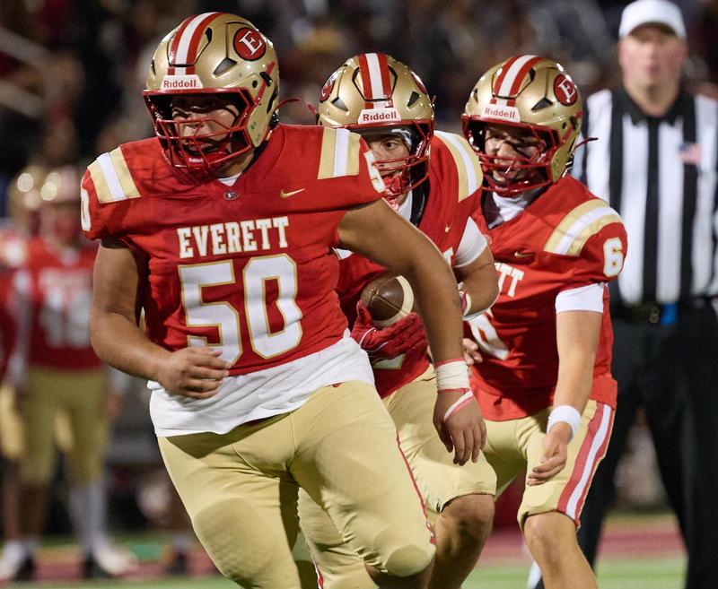 Football players in red and gold uniforms running on the field.