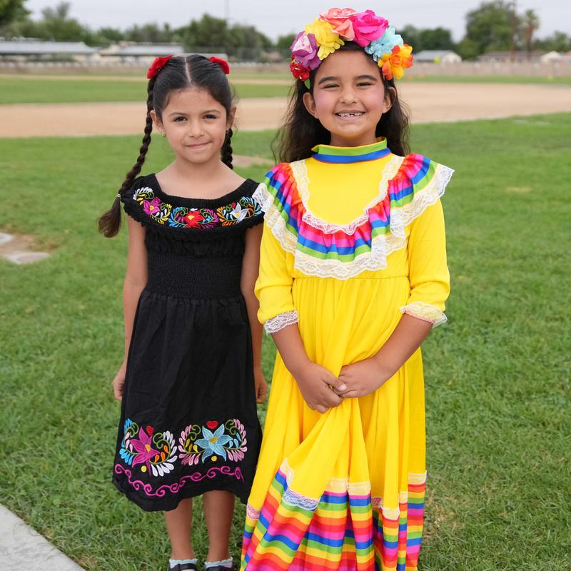 Two girls in cultural dress standing outside.