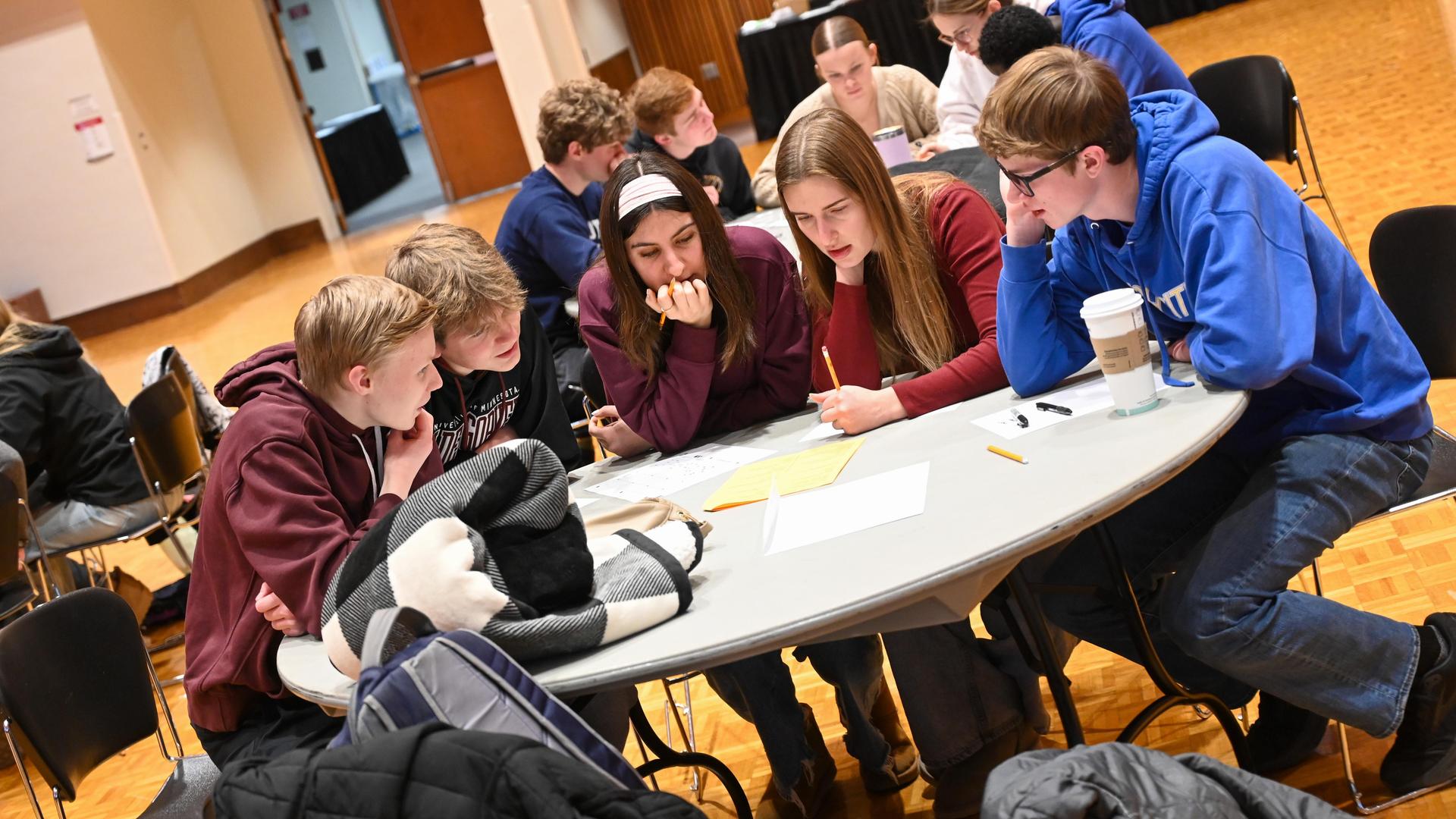 A group of five students collaborating at a round table.
