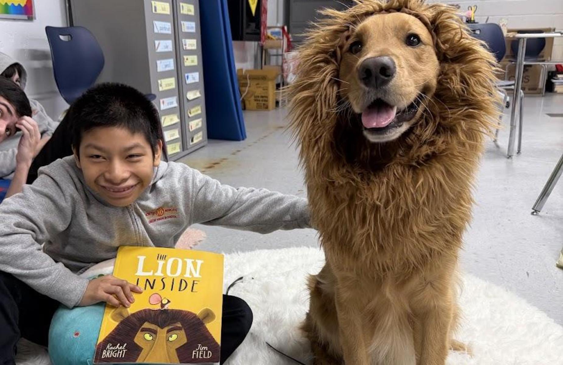 student holding a book with therapy dog dressed like lion