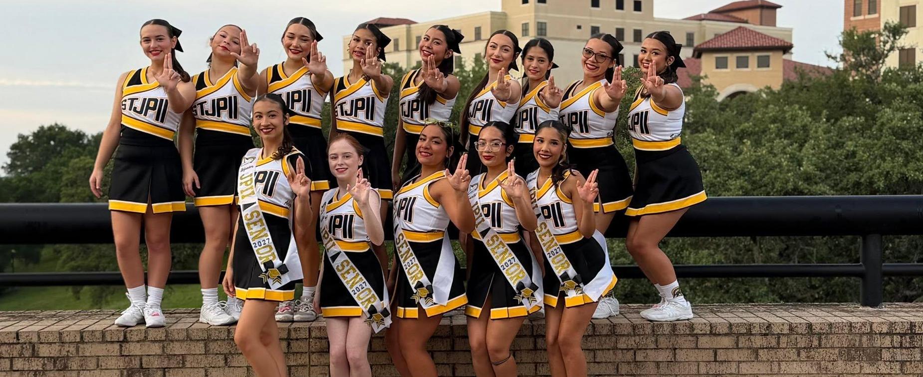 A group of cheerleaders posing together outdoors, all wearing uniforms.