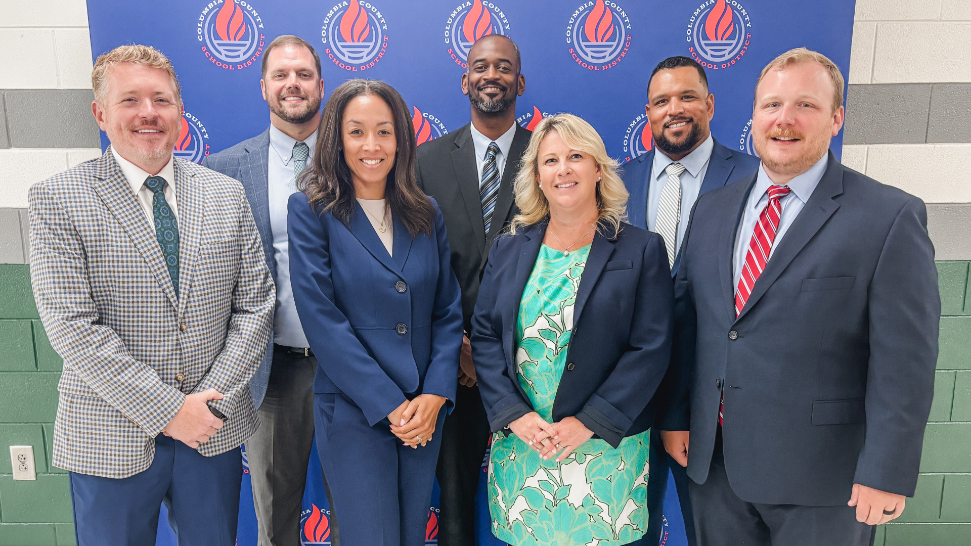 Group of seven professional individuals posing together for a photo.