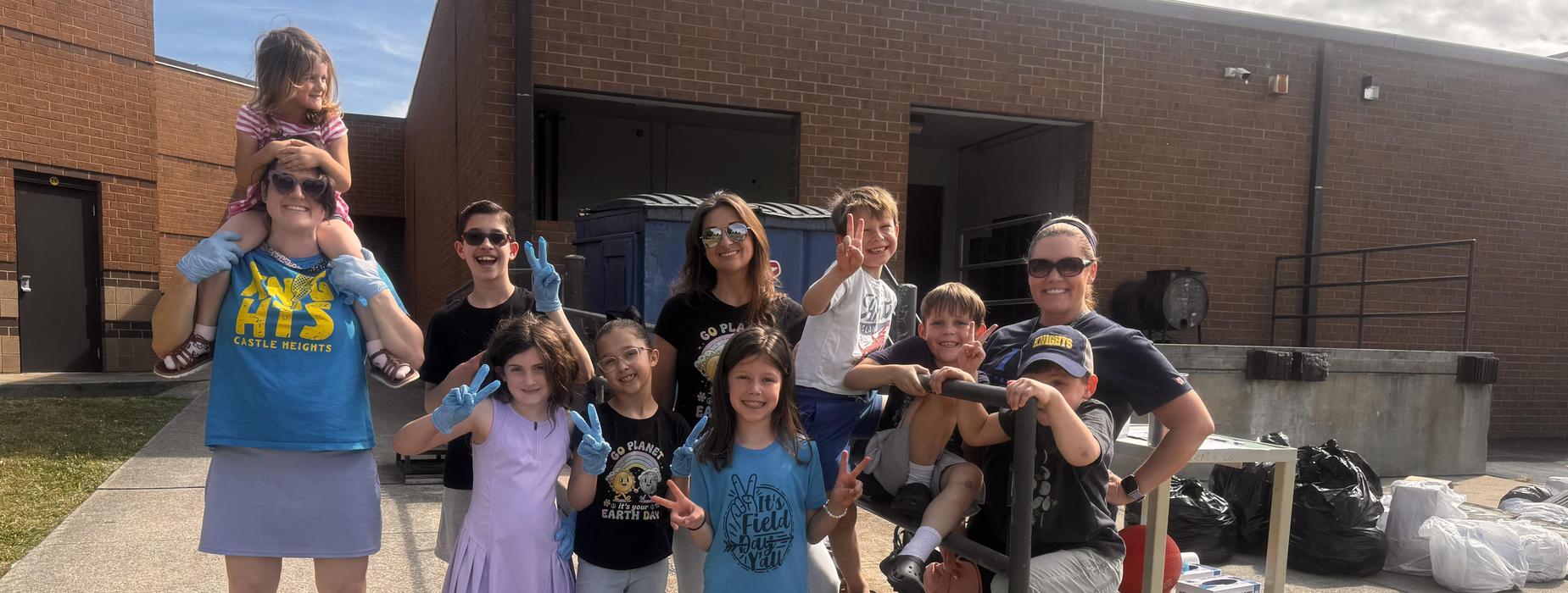 Group of children and adults posing happily outdoors.