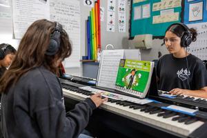 tudents at Juliette Low School of the Arts practice piano using headphones, keyboards, and instructional music materials.