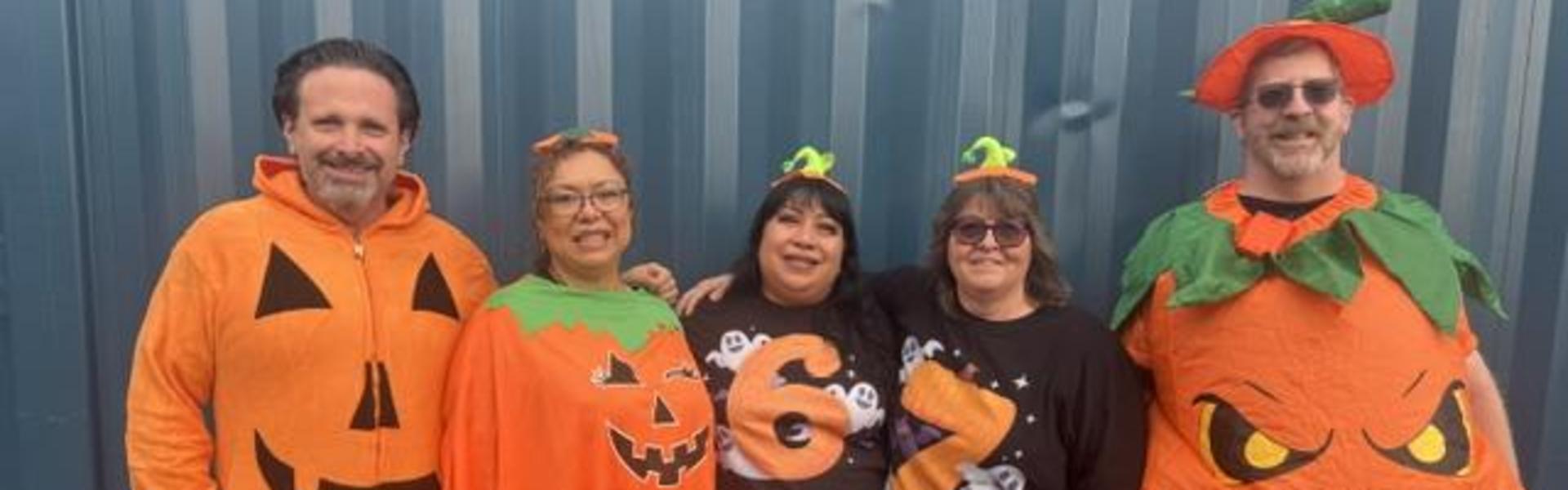 Five people in Halloween costumes, including pumpkins and ghosts.