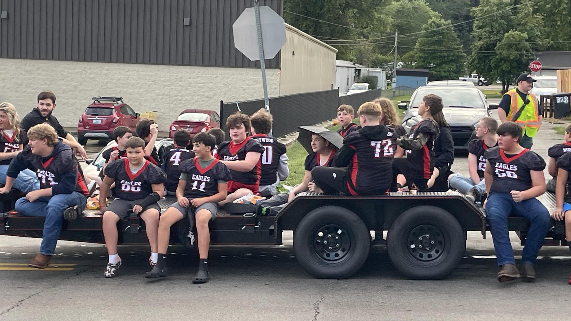 A group of young football players on a trailer during a parade.