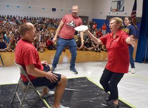 a woman dramatical throwing a pie in the face of a man sitting in a chair