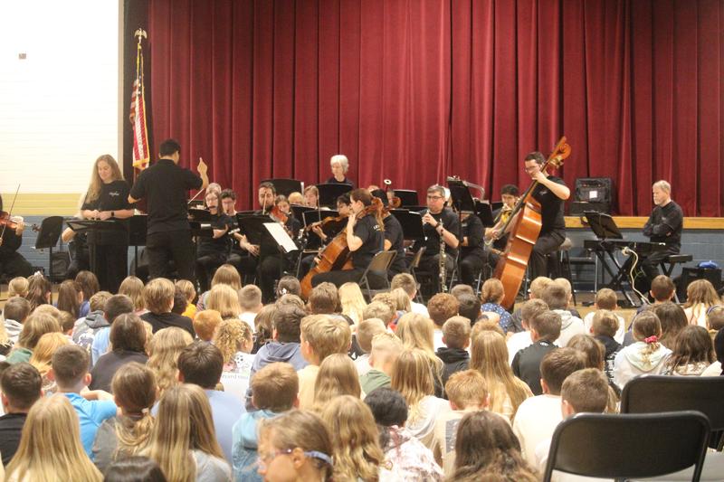 seated students look up at orchestra