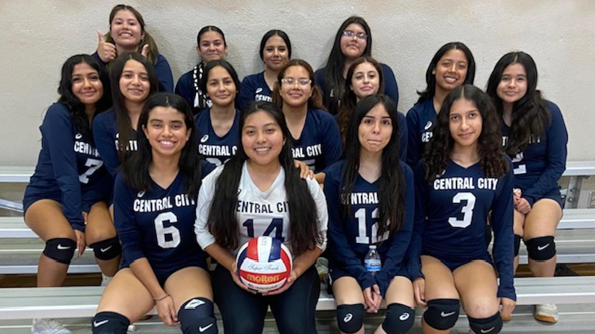 A volleyball team posing together, wearing matching uniforms.