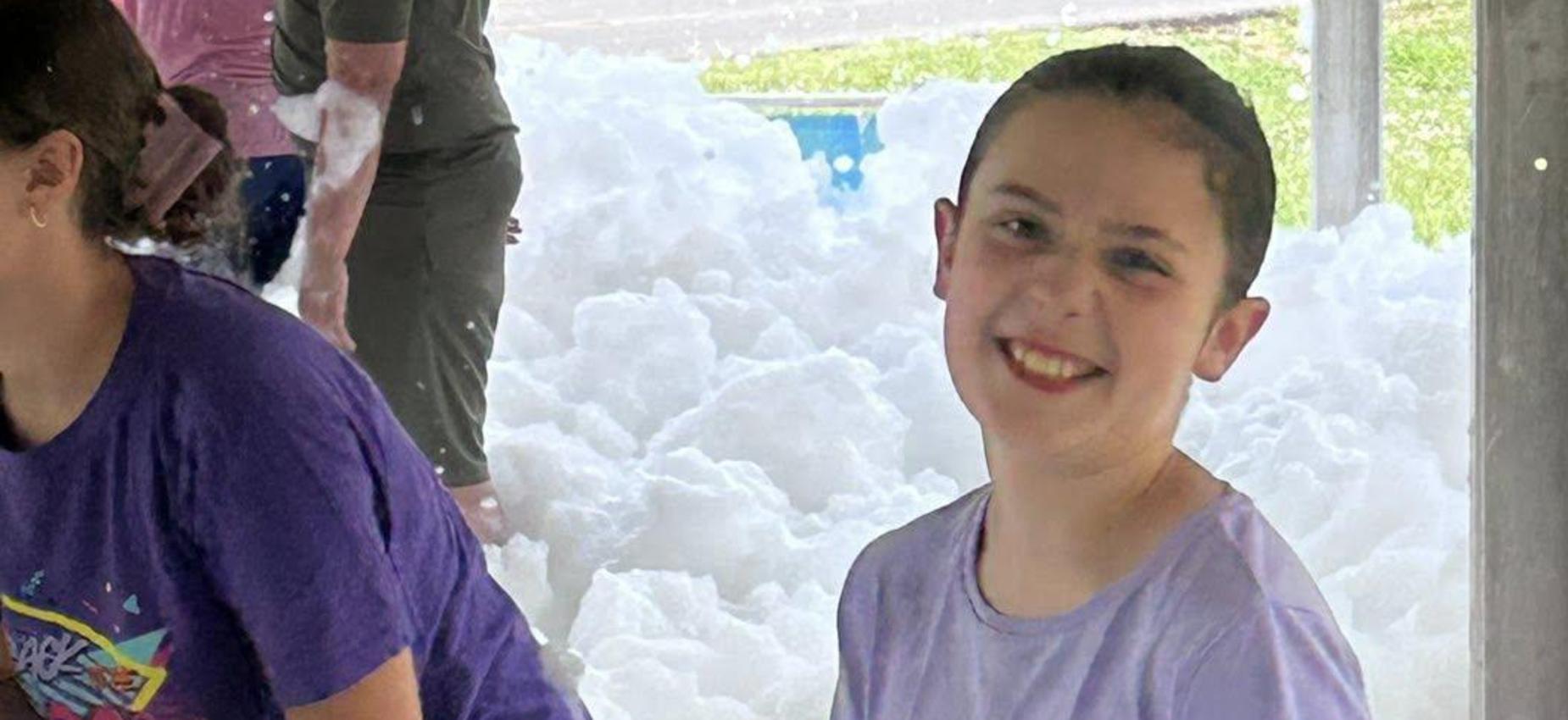 Children playing in foam under a covered structure.